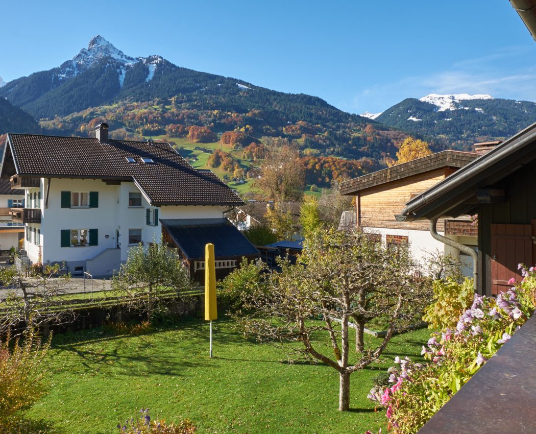 Ausblick vom Balkon auf Wiese, Nachbarhäuser und Berg Mittagspitze als Panorama