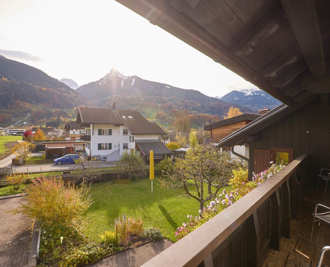 Ausblick vom überdachten Balkon auf den Garten, Nachbarhäuser und den Berg Mittagspitze