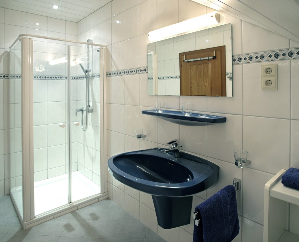 weißes Bad mit blauem Waschbecken, Spielgel und Glasdusche