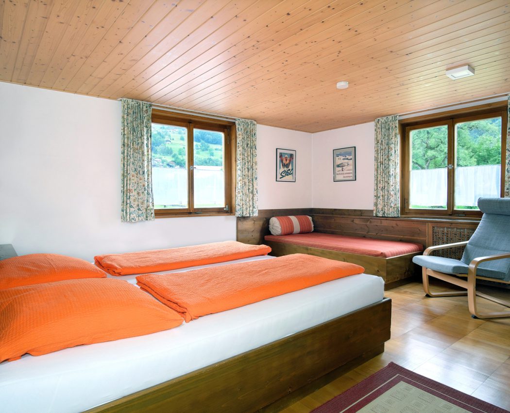 helles Schlafzimmer mit 2 Fenstern, Doppelbett und einem Einzelbett direkt vor den Fenstern