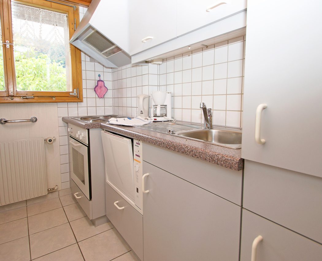 helle Küche, mit grauer Küchenzeile neben dem Fenster